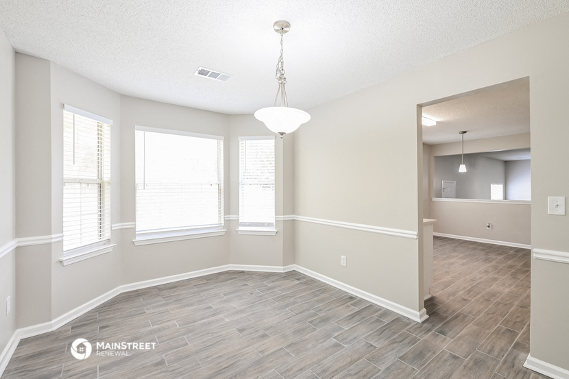 an empty living room and dining room with wood flooring and windows