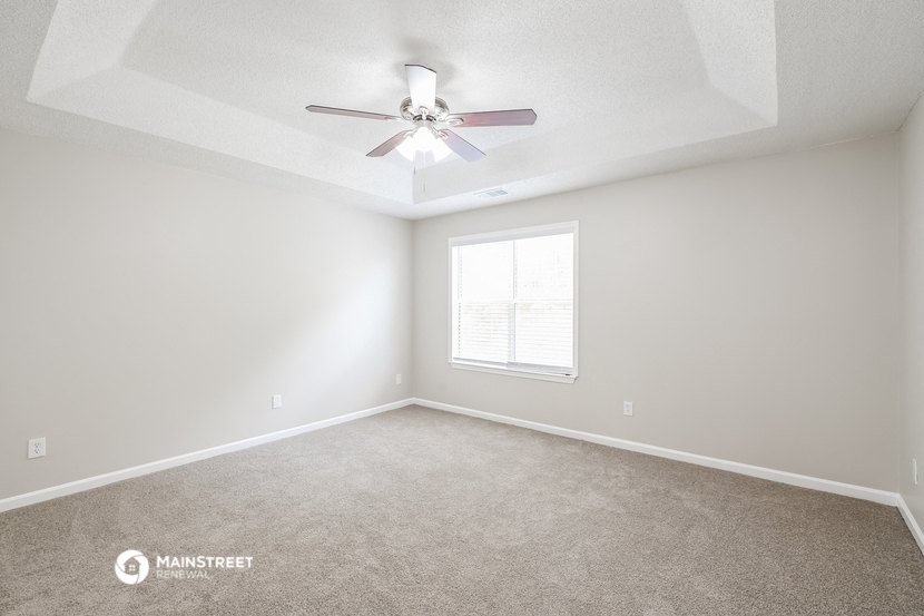 an empty room with a ceiling fan and a window