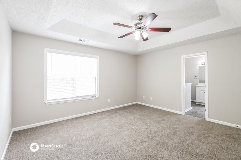 the spacious living room with ceiling fan and carpet