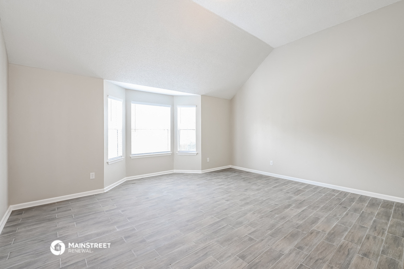 the spacious living room with wood flooring and windows