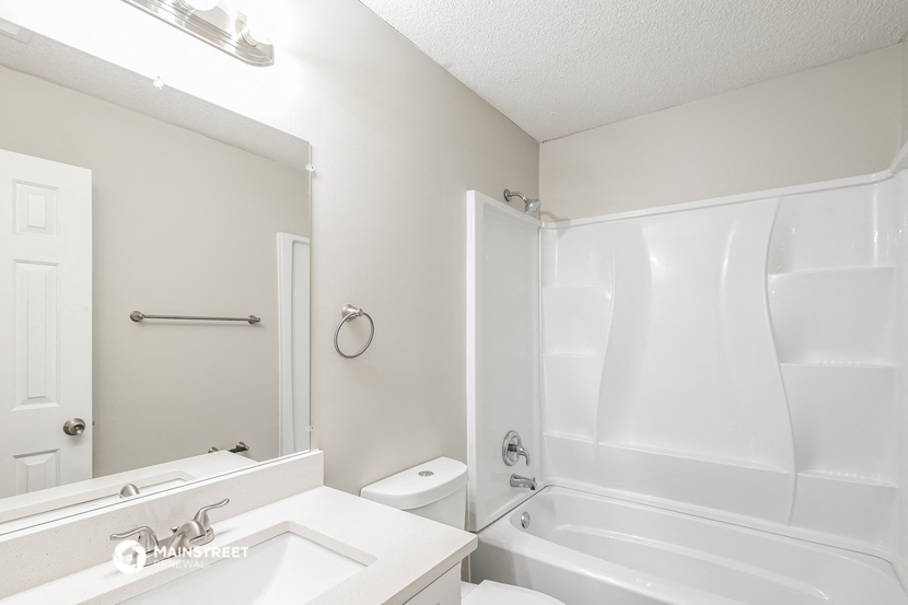 a white bathroom with a tub and a sink and a toilet