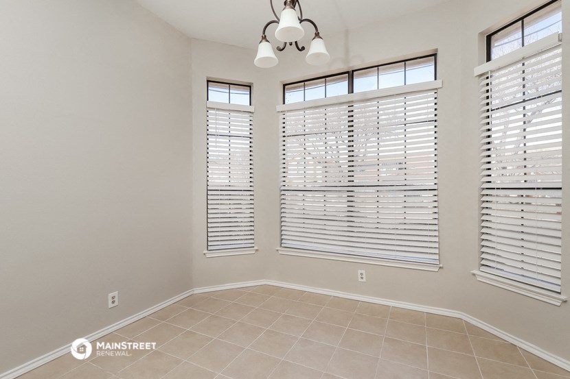 the spacious living room with three windows and a tiled floor