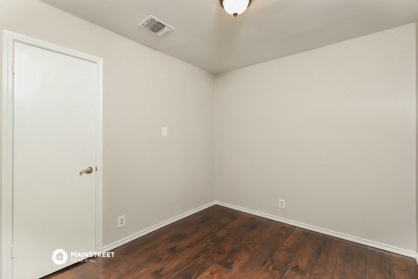a bedroom with wood flooring and white walls and a door