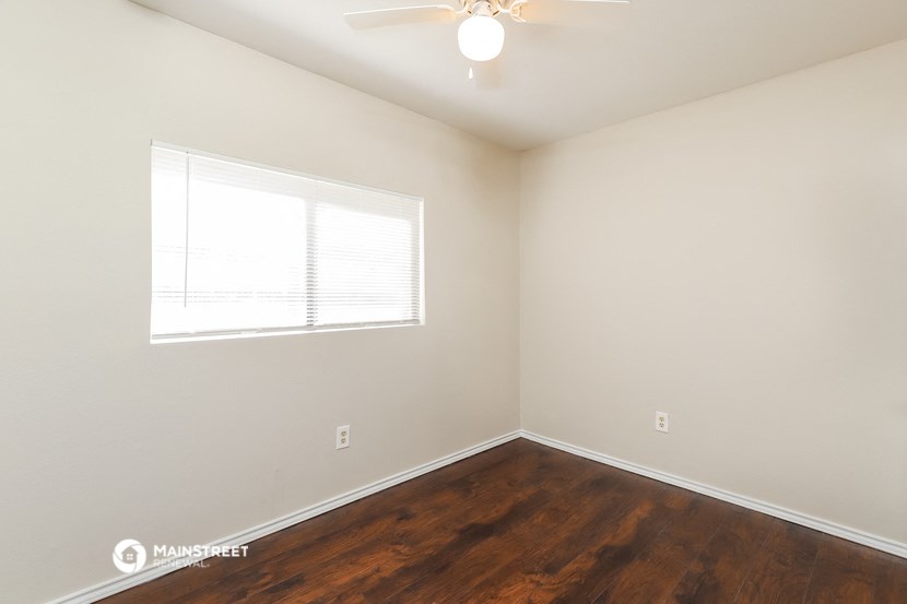 a bedroom with wood flooring and a window and a ceiling fan