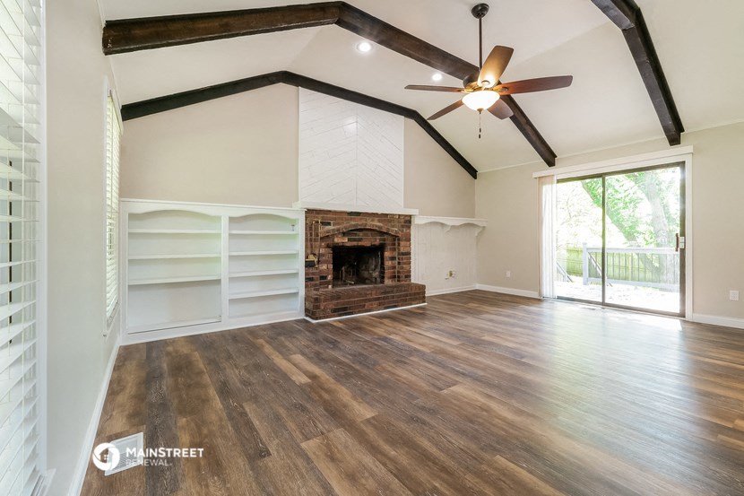 a living room with a fireplace and a ceiling fan