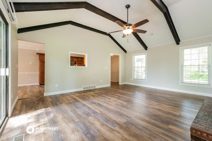 an empty living room with wood floors and a ceiling fan