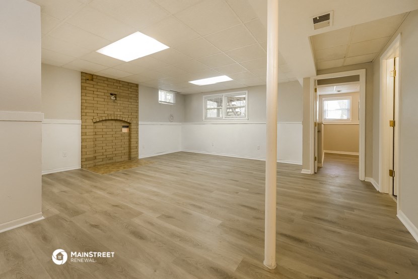 an empty living room with wood floors and a brick fireplace