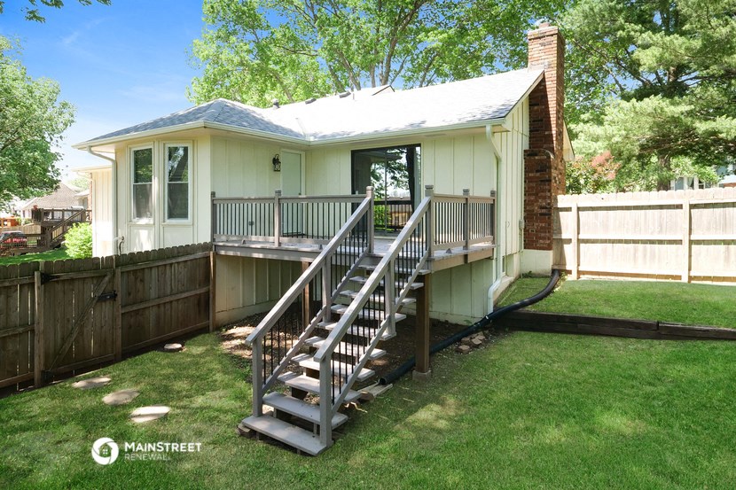 a small white house with a wooden deck and a fence