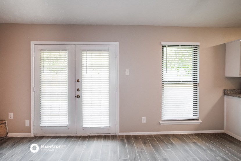 an empty living room with white doors and window blinds