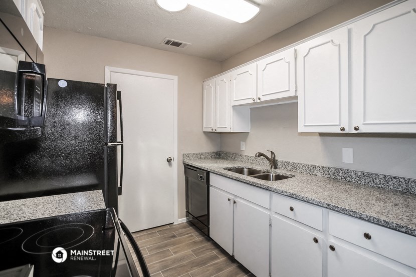 a kitchen with white cabinets and granite counter tops and black appliances