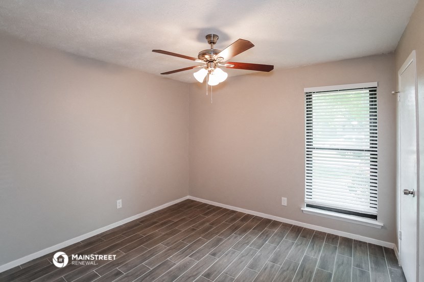 the bedroom has a large window and a ceiling fan