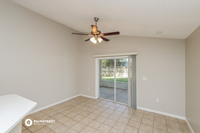 a living room with a ceiling fan and a sliding glass door to a patio