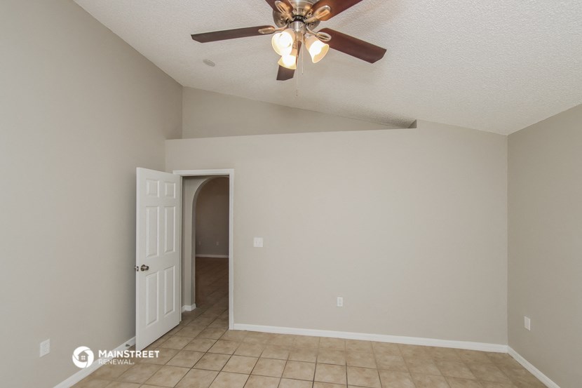 a living room with a ceiling fan and a door to a hallway