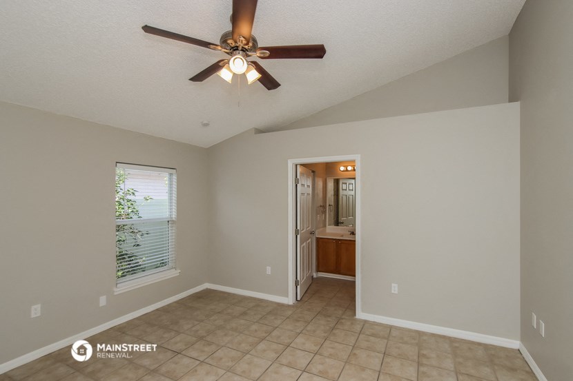 the spacious living room with ceiling fan and tile flooring