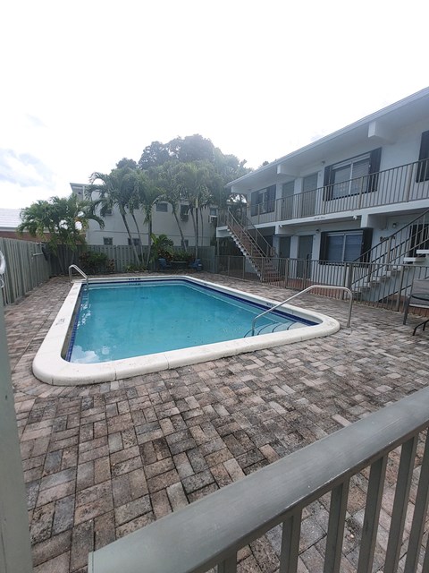 the pool is next to an apartment building with a pool