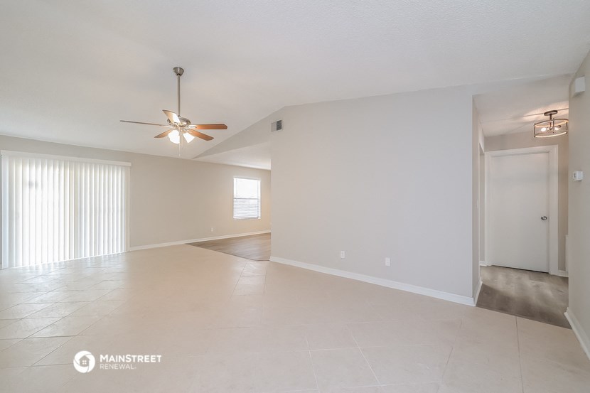 the spacious living room and dining room with a ceiling fan