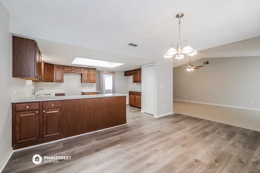 a kitchen and living room with wood flooring and wooden cabinets