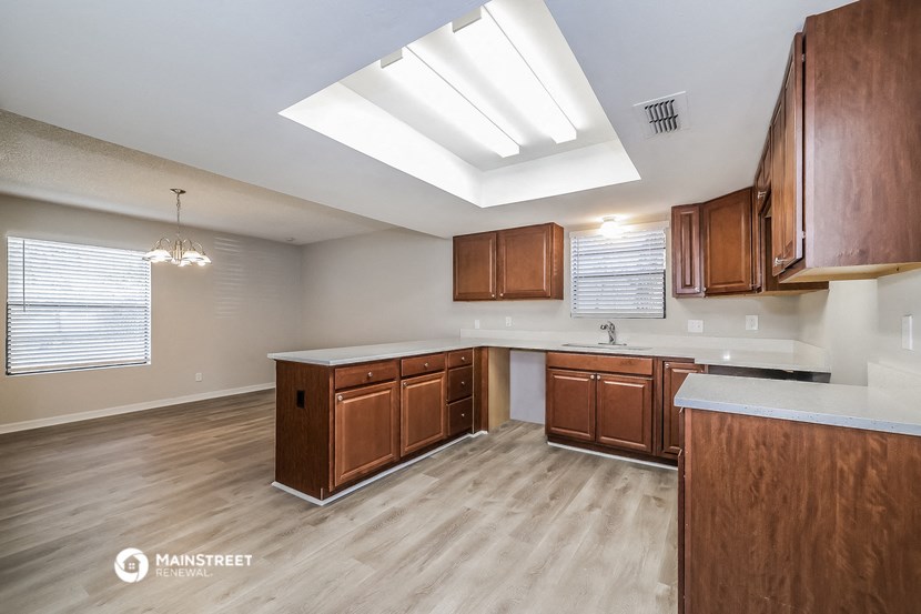 a kitchen with wooden cabinets and white counter tops and a large window