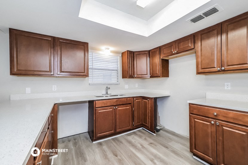 a kitchen with wooden cabinets and white counter tops and a sink