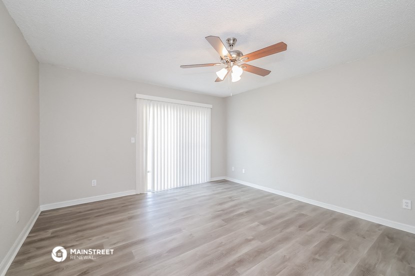 the spacious living room with ceiling fan and wood flooring