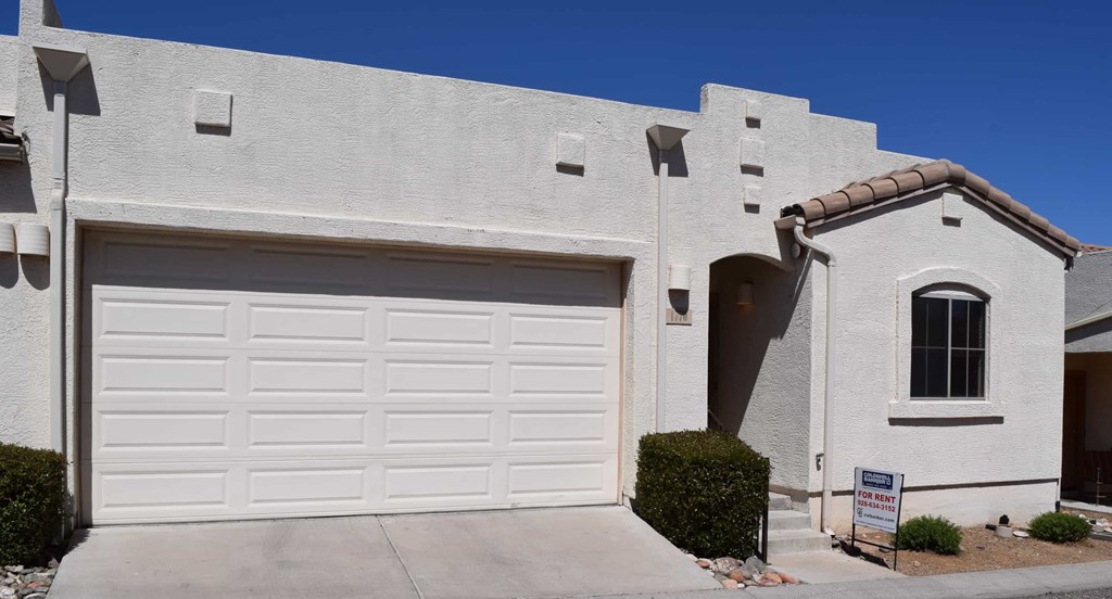 A house with a white garage door and a sign in front.