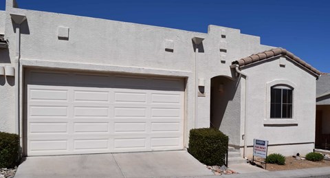 A house with a white garage door and a sign in front.