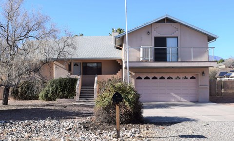 A house with a pink garage door and a balcony.