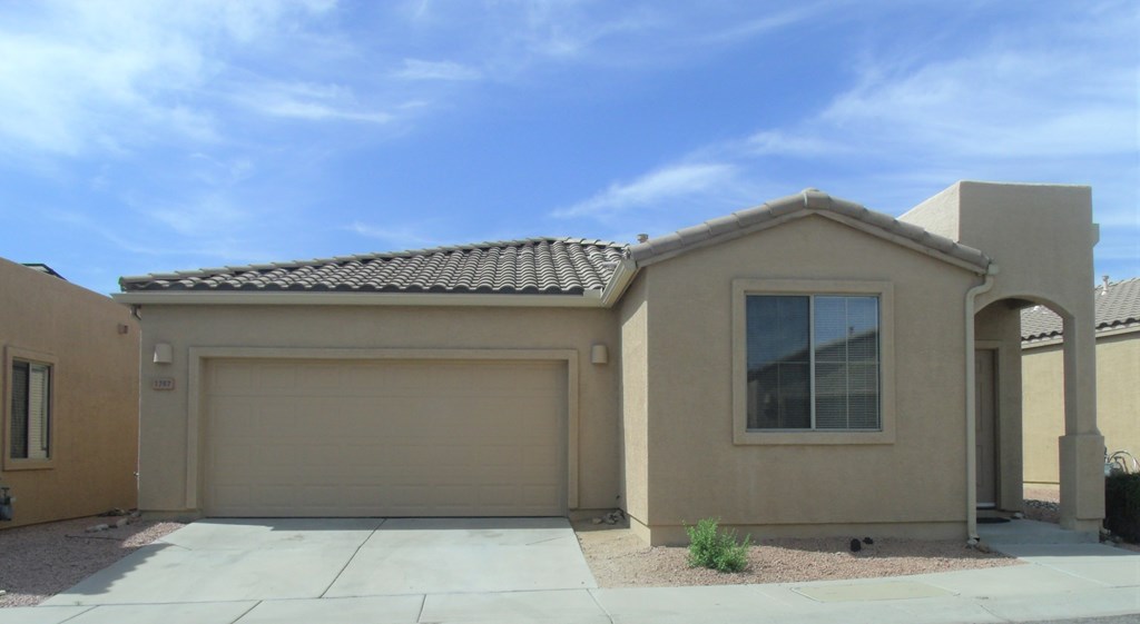 a beige house with a garage door and a blue sky