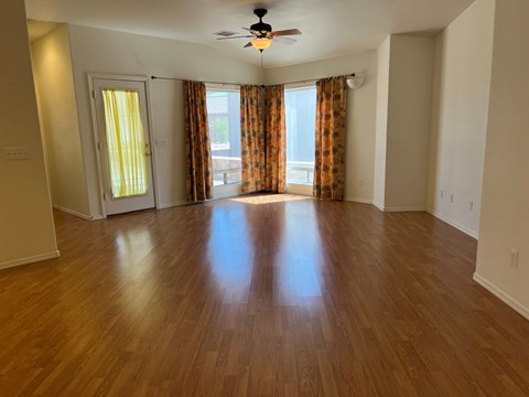 an empty living room with wood floors and a ceiling fan