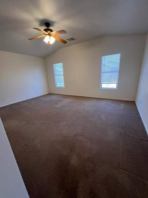 an empty room with a ceiling fan and window