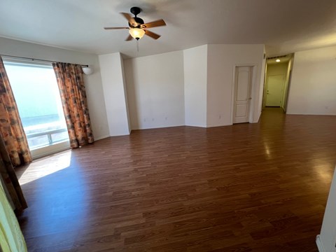 an empty living room with wooden floors and a ceiling fan