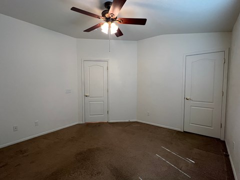 an empty room with a ceiling fan and white doors