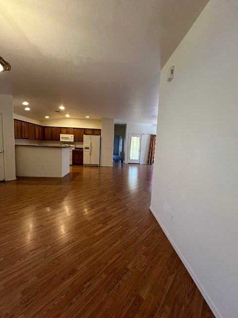 a view of an empty living room and kitchen with wood floors