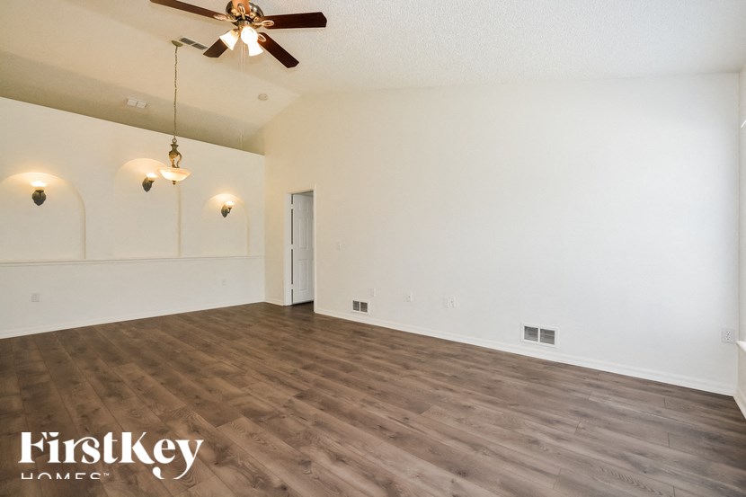 the spacious living room with wood flooring and white walls