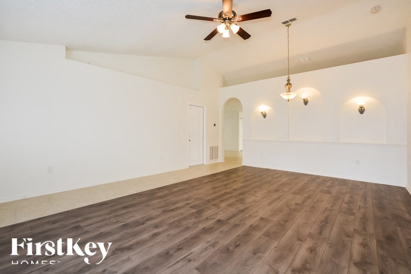 an empty living room with a ceiling fan and white walls
