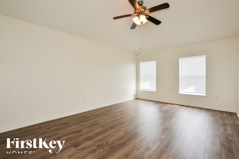 the spacious living room with wood floors and a ceiling fan
