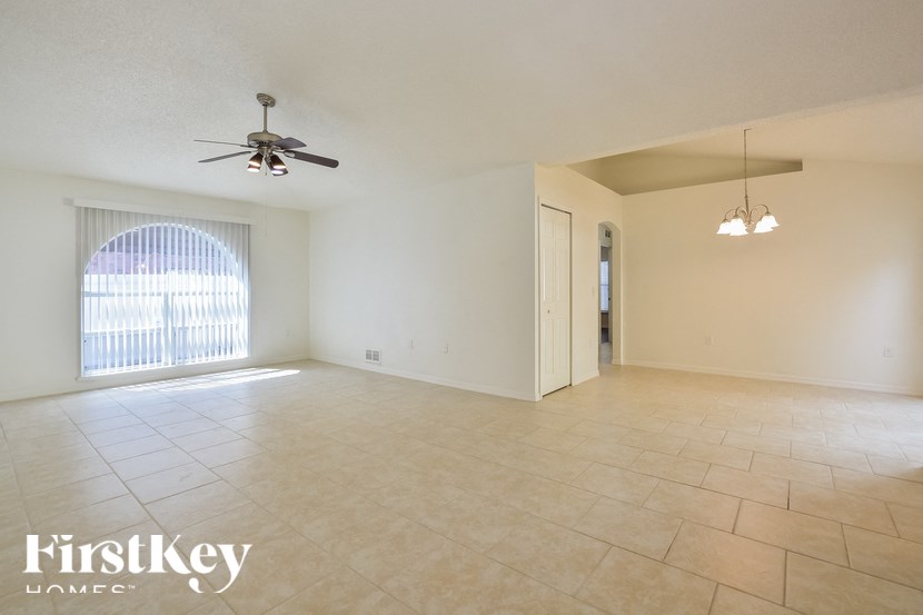 an empty living room with a ceiling fan and tiled floors
