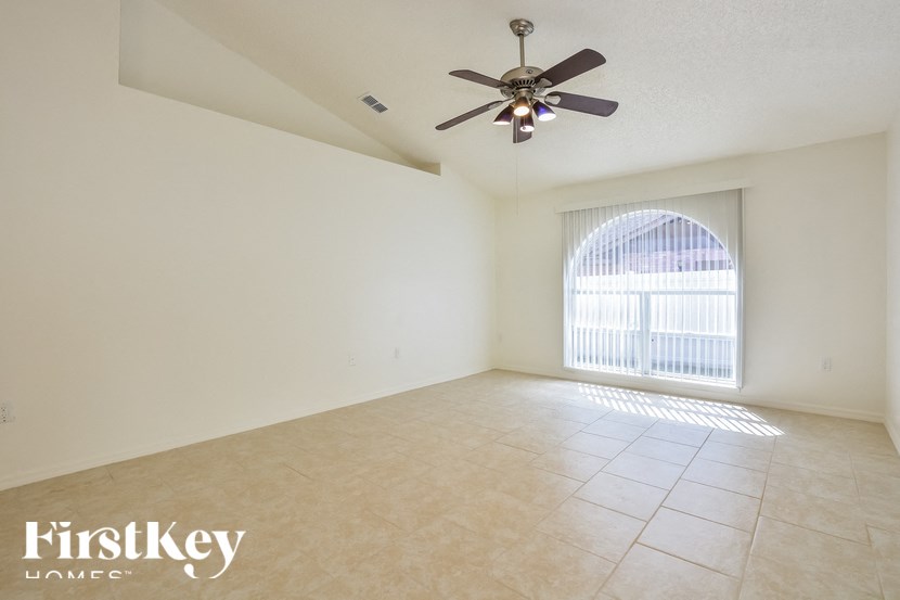 a living room with a large window and a ceiling fan