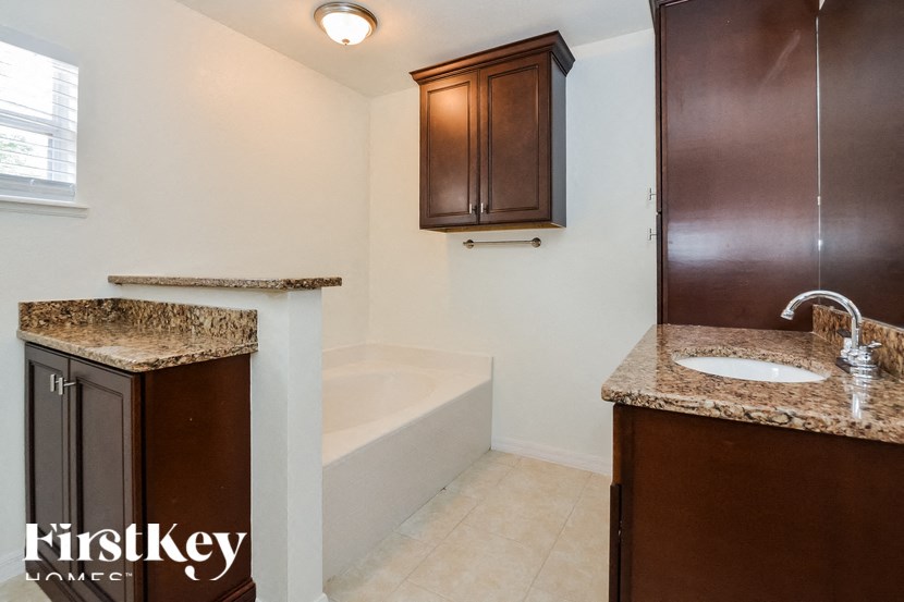 a small bathroom with a sink and a bath tub and a cabinet