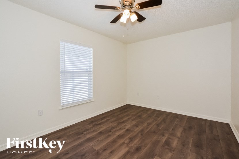 the spacious living room with hardwood flooring and a ceiling fan