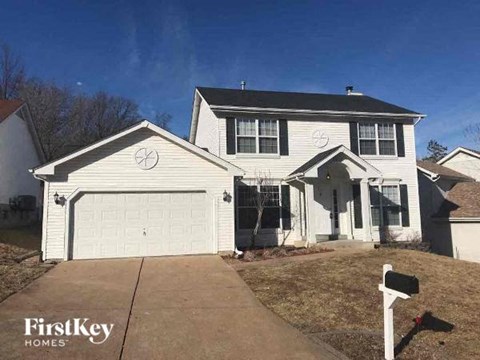 A two-story house with a garage and a driveway in front.