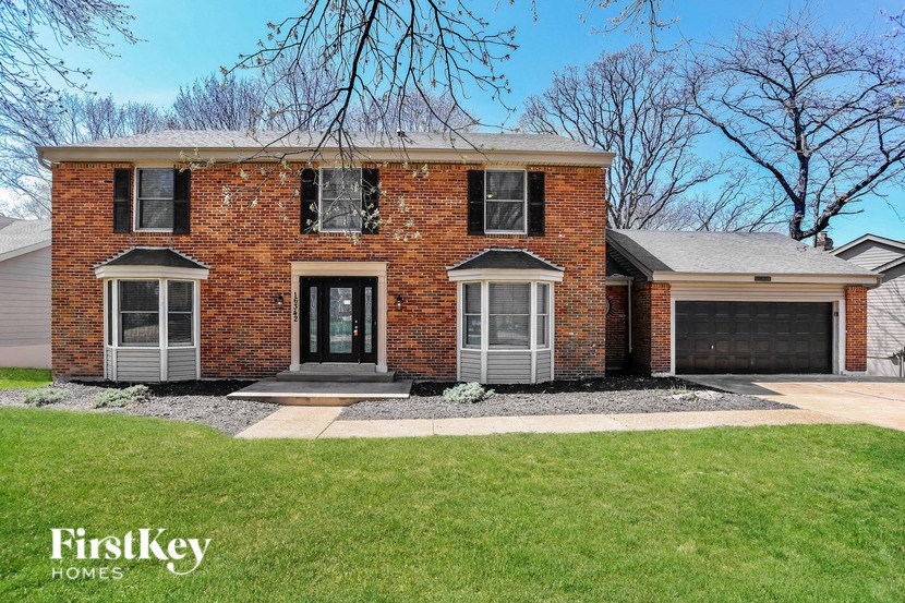 a brick house with black shutters and a lawn