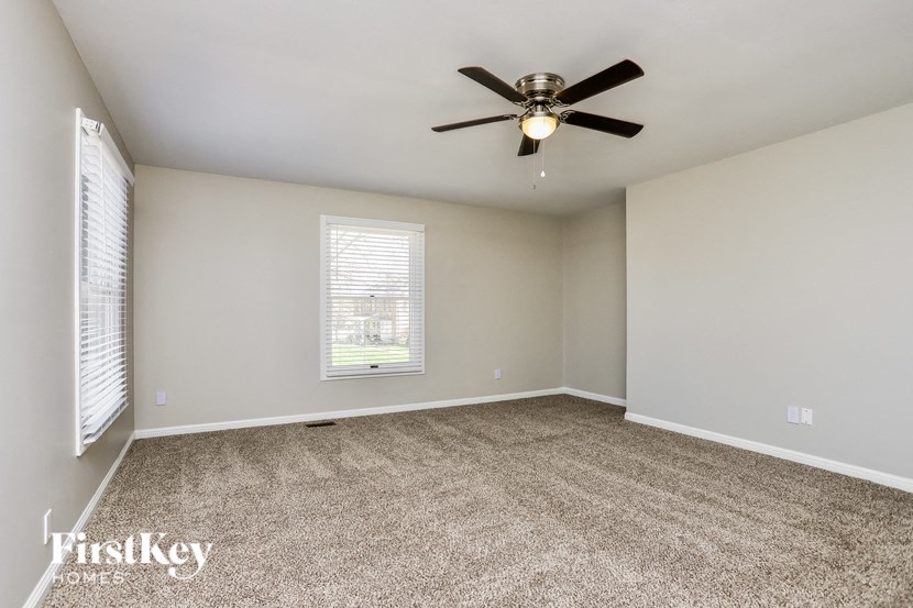 an empty living room with a ceiling fan and a window