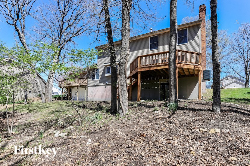 the back of a house with a wood deck and trees