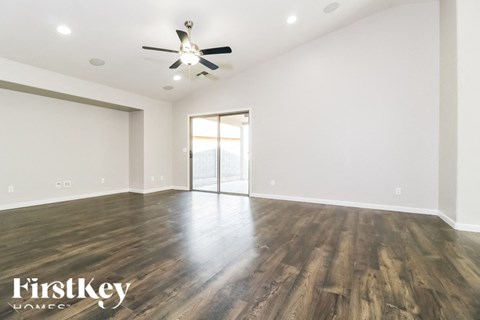 A spacious room with wooden floors and a ceiling fan.