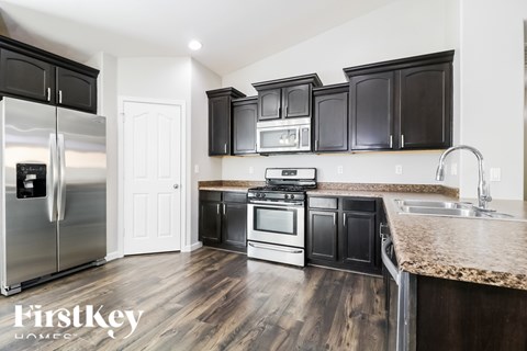 A kitchen with black cabinets and a stainless steel refrigerator.