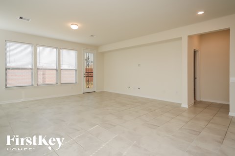 A spacious room with a tiled floor and a large window with blinds.