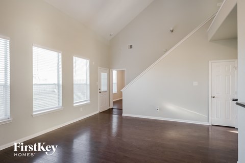 A spacious room with wooden floors and a staircase leading to another room.