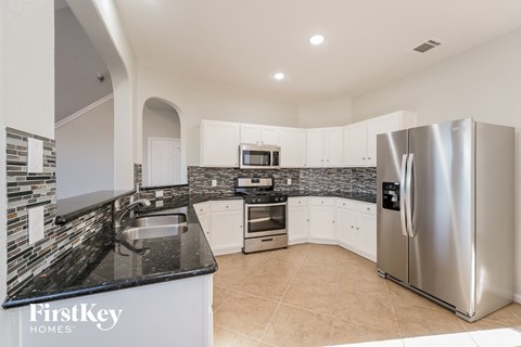A modern kitchen with a stainless steel refrigerator and a black countertop.