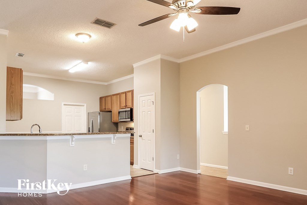 an empty living room and kitchen with a ceiling fan